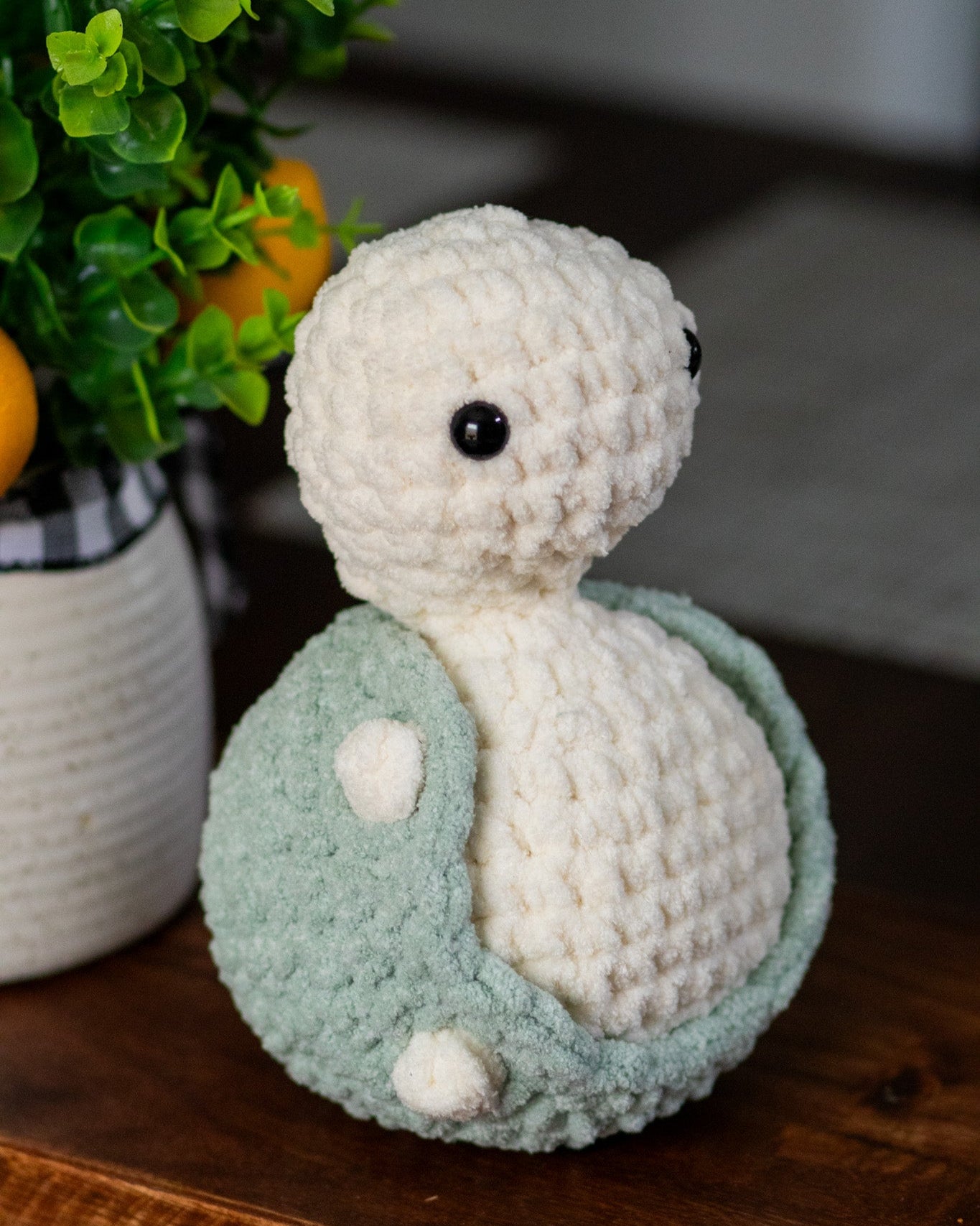 Crocheted turtle toy on a wooden surface with a blurred background